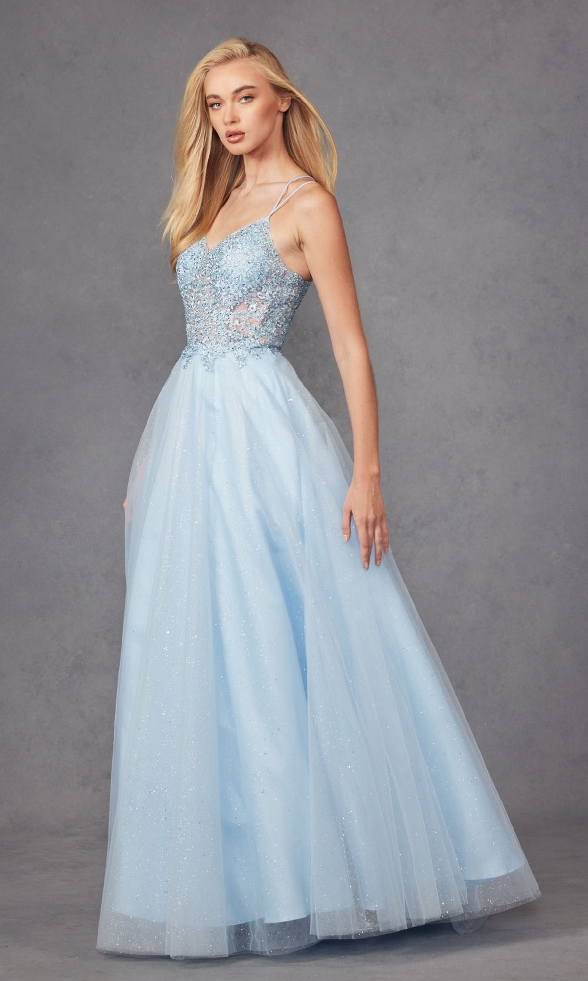 A woman wears the Glitter-Tulle Long Corset-Back Prom Ball Gown 268—light blue, floor-length with a beaded bodice and tulle skirt—standing against a plain gray background.